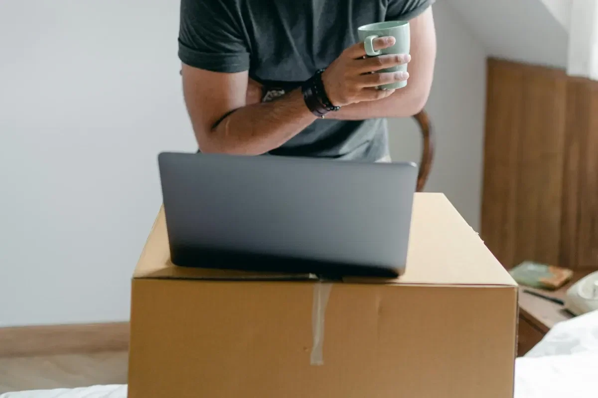 homem com notebook alugado sob caixa