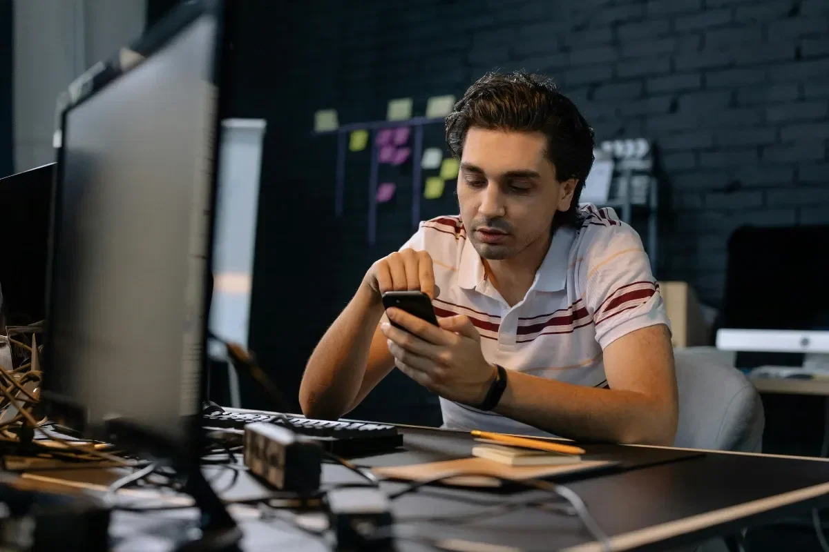 homem com celular e computador